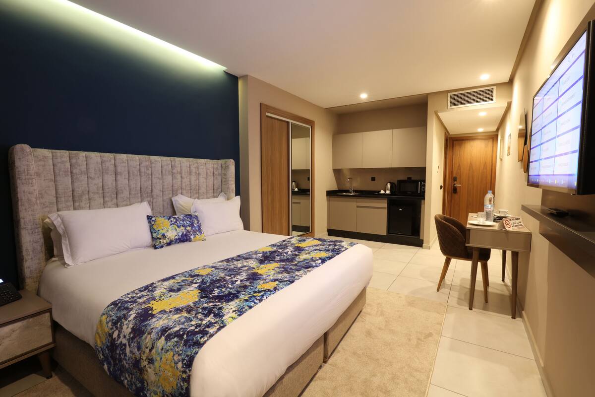Una habitación de hotel moderna con una cama grande, un escritorio y una televisión.