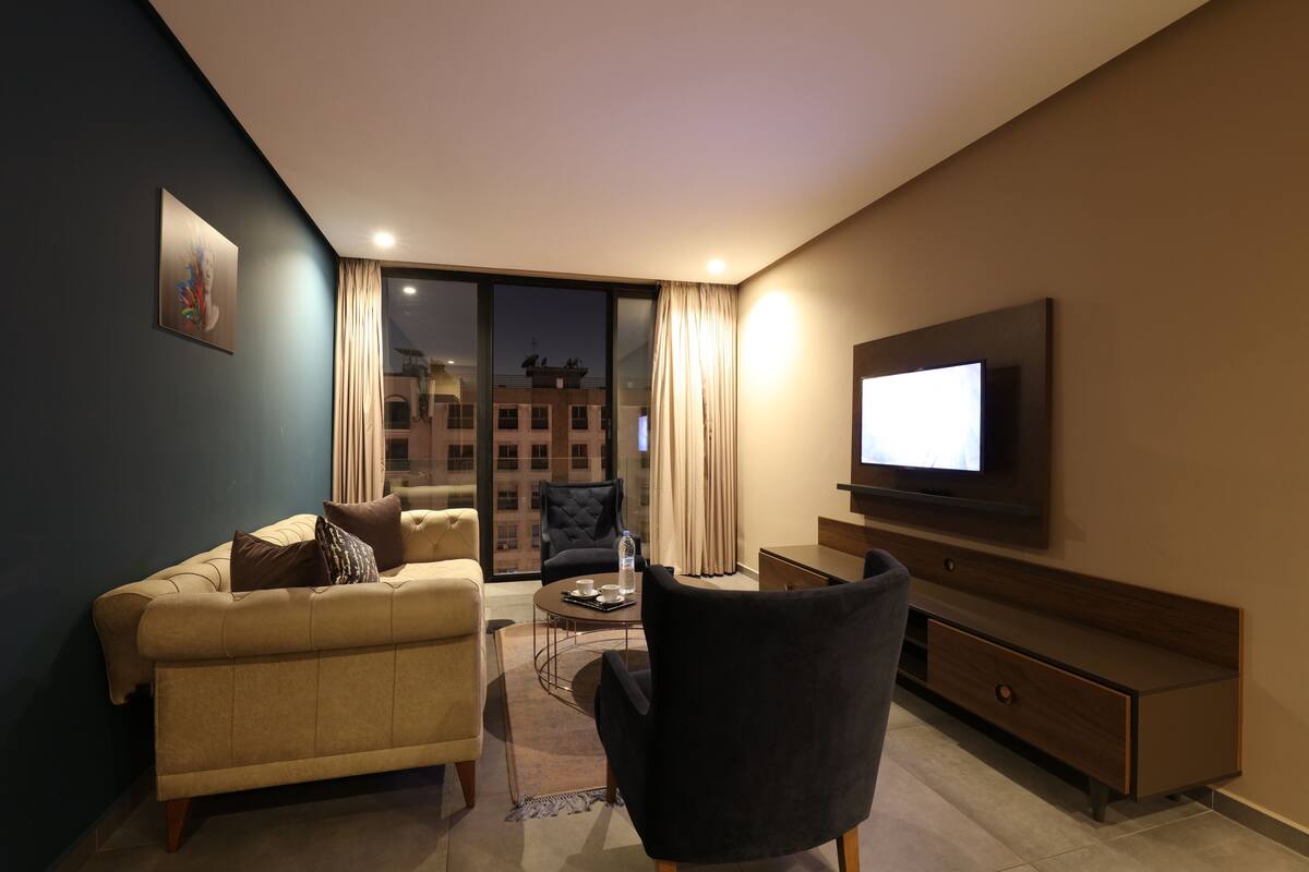 Una sala de estar moderna con un sofá, un sillón, una mesa de centro y un televisor de pantalla plana montado en la pared.
