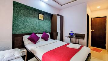 Habitación de hotel con cama, mesita de noche, escritorio y pared verde con textura.