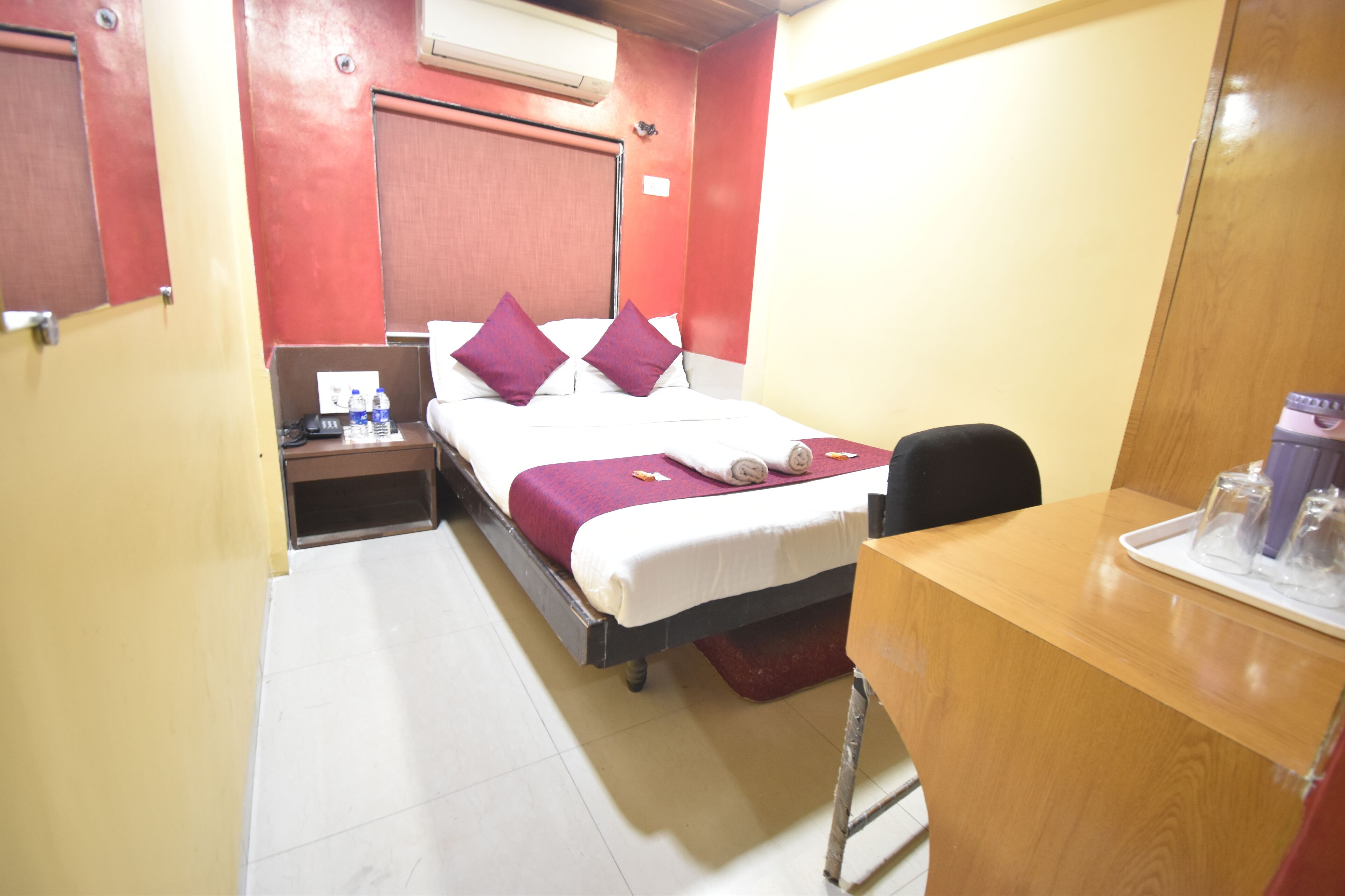 Una habitación de hotel con cama, escritorio y mesita de noche.