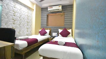 A hotel room with two beds, a wooden desk, an air conditioning unit, and a patterned wall.