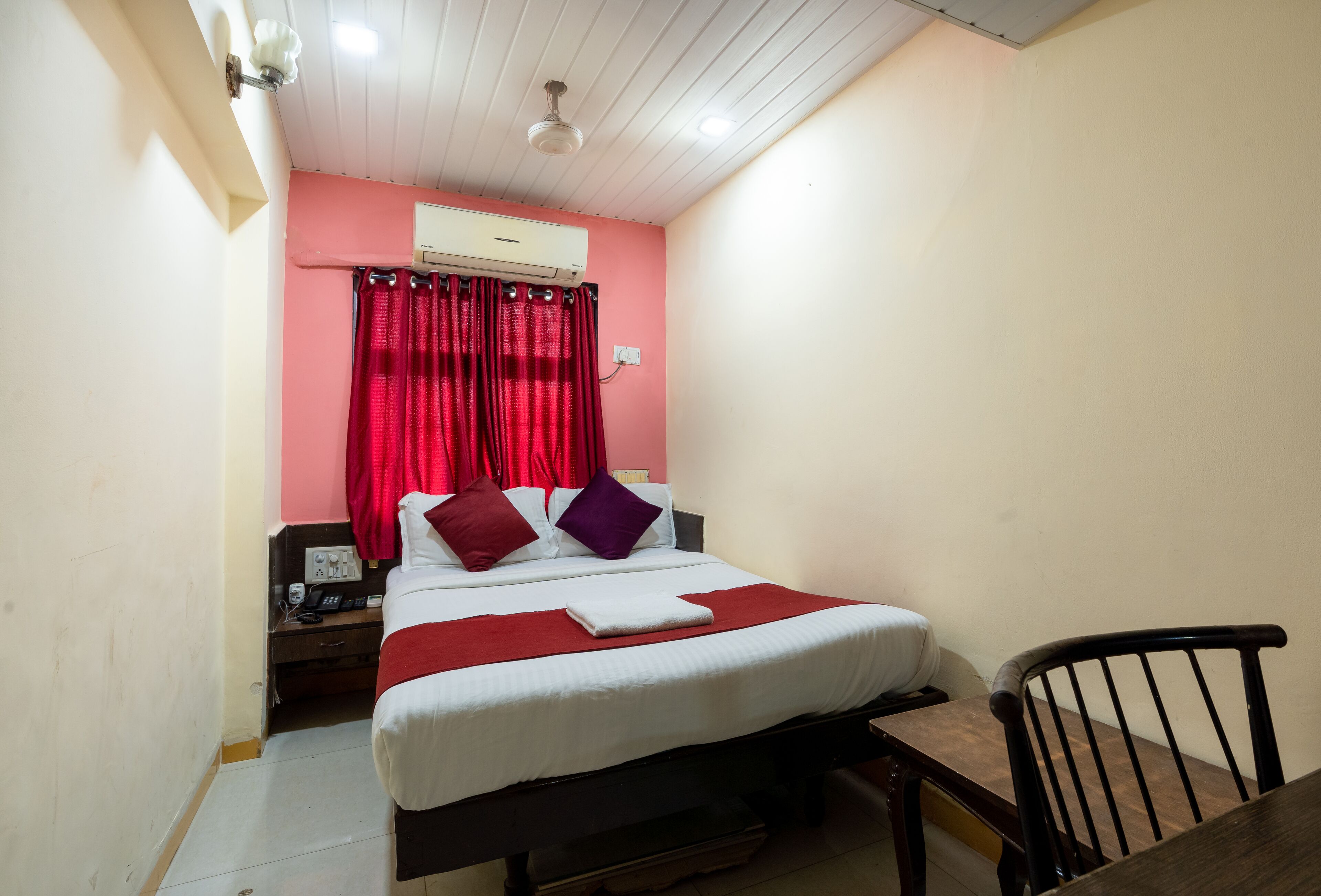 A small, neatly arranged bedroom with a bed, a nightstand, a chair, and a table.
