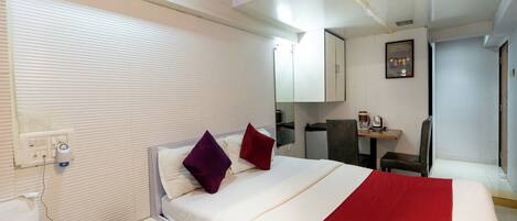 A hotel room with a bed, a desk, a chair, a telephone, and a coffee maker.