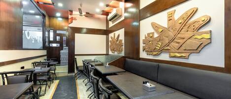A restaurant interior with long tables, booths, and a central seating area.