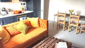 Ein gemütlicher Wohnbereich mit einer Couch, einem Holztisch und einem farbenfrohen Teppich.