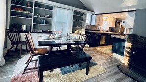 Een eetgedeelte met een tafel gedekt voor zes personen, omringd door stoelen, in een kamer met een schuine kap en een open haard.