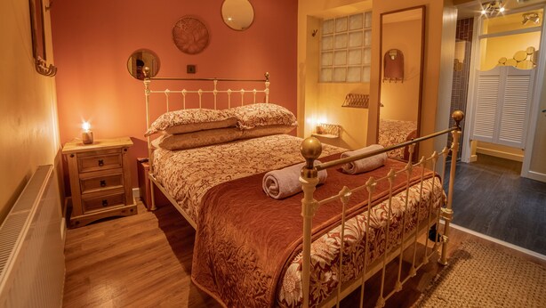 Un dormitorio con cama, mesitas de noche, un espejo y una ventana con persianas.