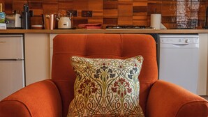 Una cocina con un sillón rojo, un cojín estampado y varios electrodomésticos.