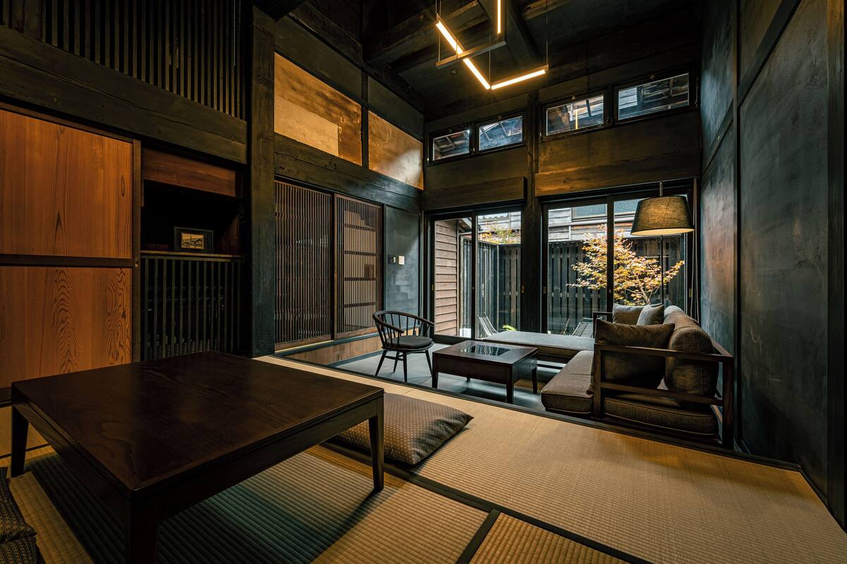 A modern interior with a wooden table, seating, and large windows.