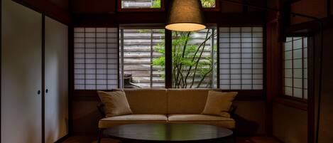 A traditional Japanese room with sliding doors, a sofa, a table, and a hanging lamp.