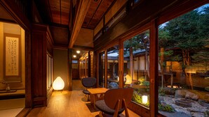 A traditional Japanese interior with wooden flooring, a tatami mat, a low table, and a chair. - BYAKU Narai (Shiojiri)