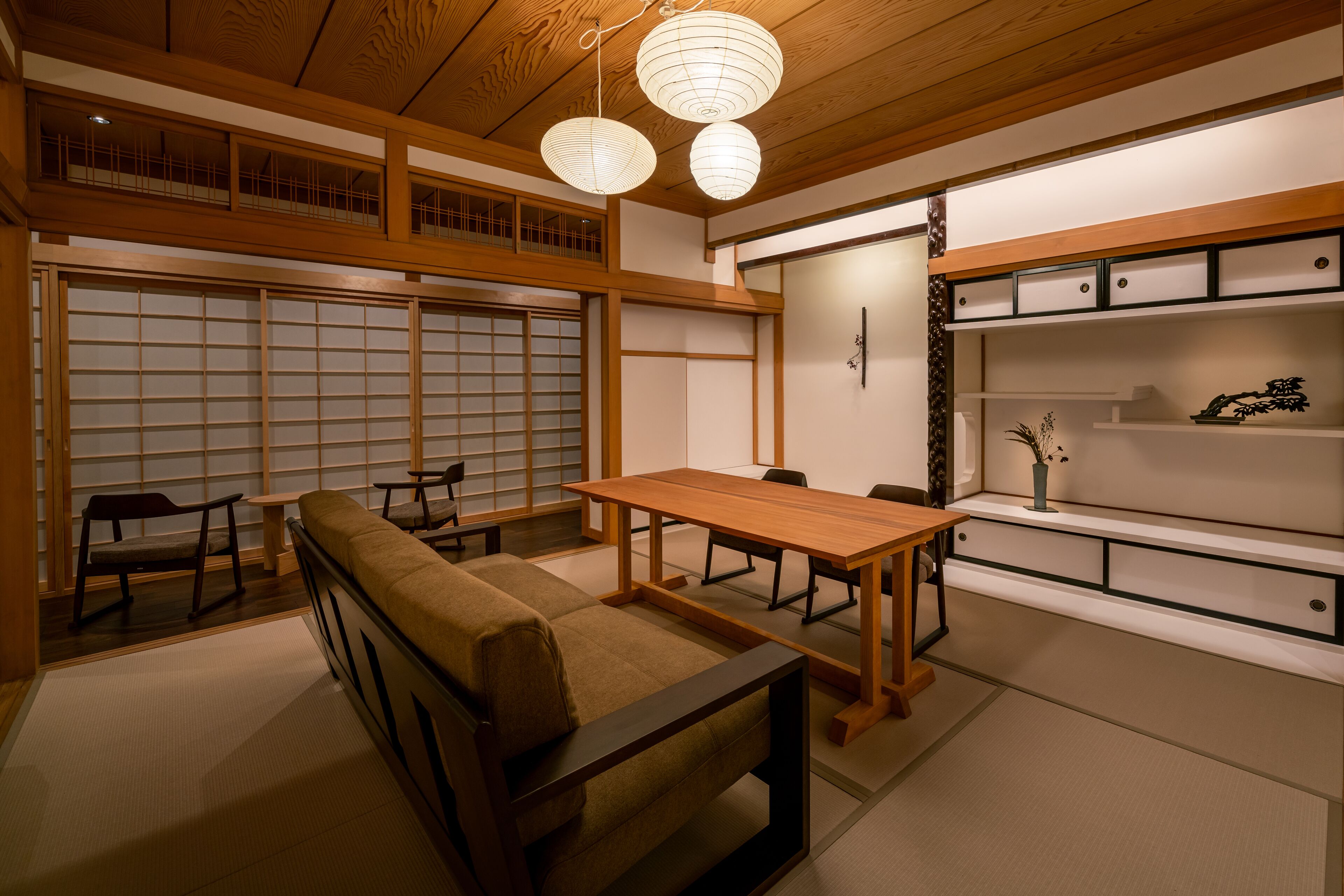 A traditional Japanese room with tatami flooring, a low wooden table, a cushioned bench, and sliding doors.