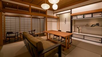 A traditional Japanese room with tatami flooring, a low wooden table, a cushioned bench, and sliding doors.