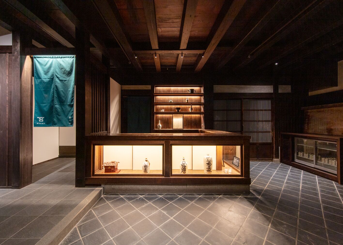 A traditional Japanese interior with a wooden ceiling, a display case with items, and a tiled floor.