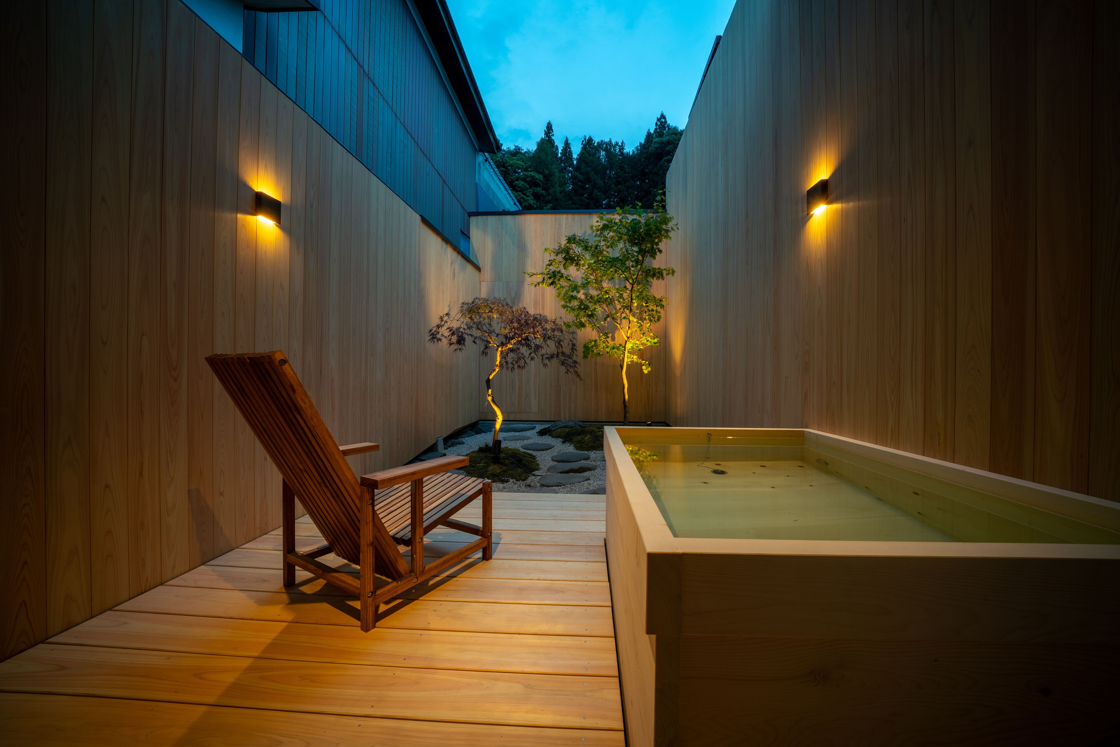 Une terrasse en bois avec un jacuzzi et une chaise en bois.