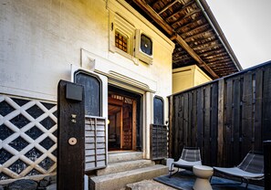 A traditional building with a wooden door, steps leading to a porch, and two lounge chairs outside. - BYAKU Narai (Shiojiri)