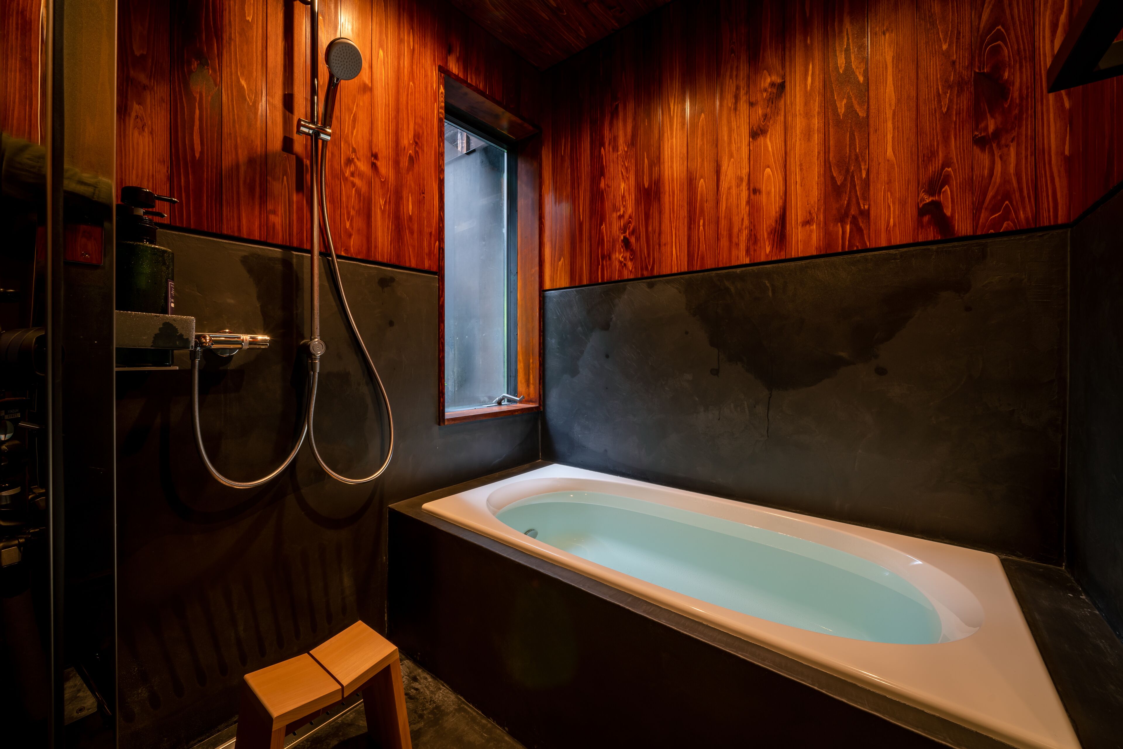 A modern bathroom with a wooden interior, a large bathtub, and a shower area.
