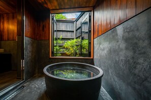 A modern bathroom with a large bathtub, a window with a view of greenery, and wooden walls. - BYAKU Narai (Shiojiri)