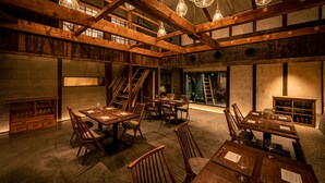 A spacious interior with wooden beams, multiple dining tables, and hanging light fixtures. - BYAKU Narai (Shiojiri)