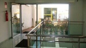 Un interior moderno de hotel con barandilla de vidrio, un extintor y vistas al área del balcón exterior.