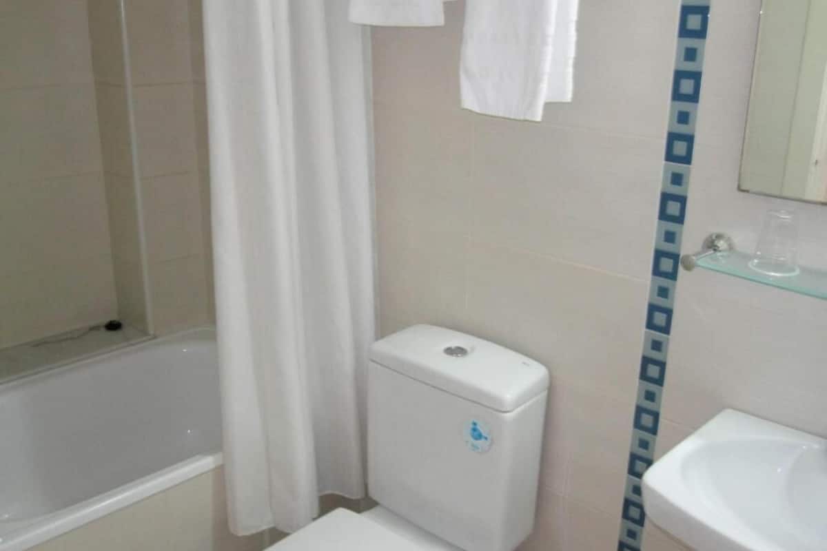 Un baño con inodoro, lavabo y zona de ducha.
