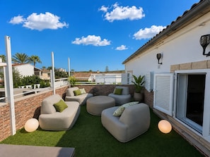 Terraza en la azotea con mobiliario exterior y vista panorámica de la ciudad.