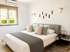 A bedroom with a bed, bedside table, wall-mounted zebra decorations, and an air conditioning unit. - Villa Colibrí, con piscina privada para 6 personas (Son Ferrer)