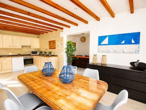 A modern kitchen with wooden cabinets, a dining table with chairs, and a black island.