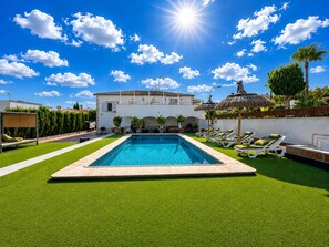 A swimming pool with a surrounding lawn, lounge chairs, and a building in the background. - Villa Colibrí, con piscina privada para 6 personas (Son Ferrer)