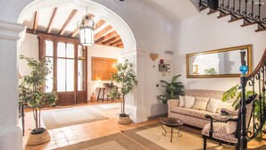 A spacious living area with a wooden staircase, a sofa, and potted plants. - León de Sineu - Ten Bedroom Villa, Sleeps 21 (Sineu)