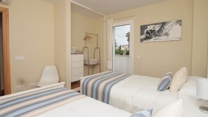 A hotel room with two beds, a chair, a desk, a wardrobe, and a painting on the wall. - Beach Houses Playa de Muro twins SEGALLS Y FOTGES (Muro)