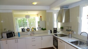 A modern kitchen with white cabinets, a built-in oven, a sink, and a window with a view of greenery. - Beach Houses Playa de Muro twins SEGALLS Y FOTGES (Muro)