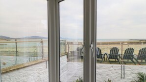 Una stanza con un'ampia finestra che si affaccia su una spiaggia, con sedie e una recinzione.
