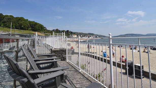 Una passeggiata lungomare con panchine, un recinto bianco e una spiaggia sullo sfondo.
