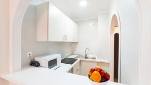 A modern kitchen with white cabinets, a microwave, a sink, and a fruit bowl on the counter. - Casa vida 1 bedroom · Casa vida 1 bedroom · Family Friendly Apartment ¨Casa Vida¨ (Santa Ponça)