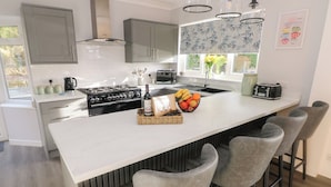 Une cuisine moderne dotée d’un îlot central, de tabourets de bar et d’une cuisinière intégrée.