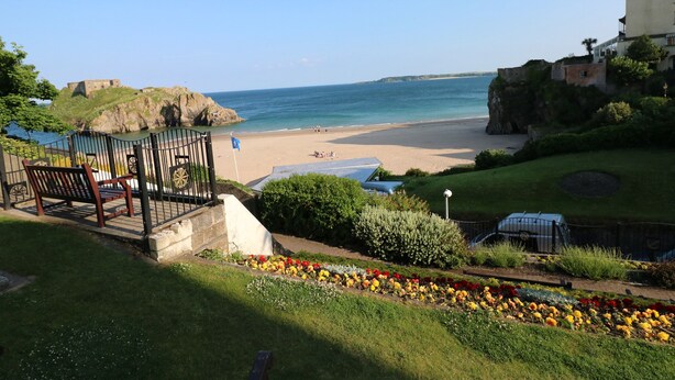 Une vue sur la côte, avec une plage, un bâtiment historique et un jardin fleuri.