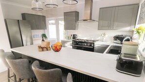 Une cuisine moderne dotée d’un îlot central, de tabourets de bar, d’une cuisinière et d’un grille-pain.