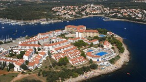 Ett flygbildsfoto av en kustort med flera byggnader, en småbåtshamn och ett strandområde.