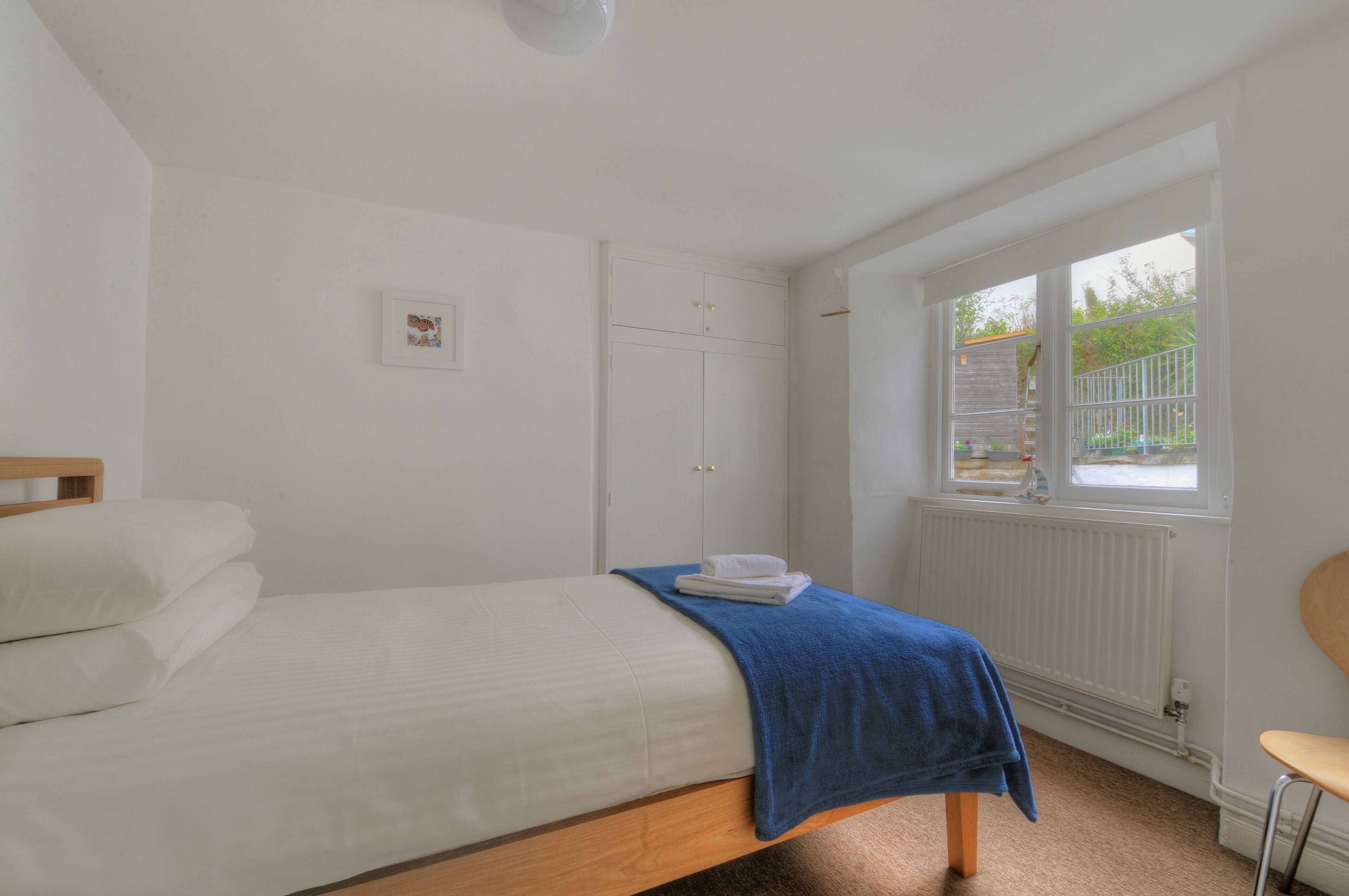 A bedroom with a bed, a window with a view, a radiator, and a door.