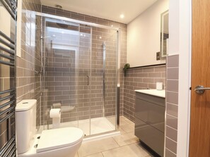 A modern bathroom with a glass-enclosed shower, a toilet, and a sink with a mirror above it. - Ash Cottage (Ilfracombe)