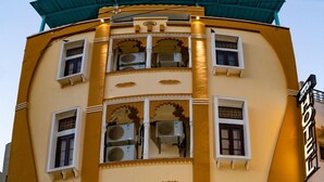 Un hotel con diseño arquitectónico tradicional, que cuenta con varios balcones y unidades de aire acondicionado.