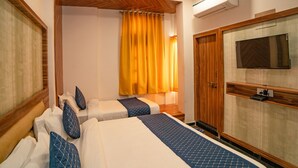 Habitación de hotel con dos camas, televisión, armario y aire acondicionado.