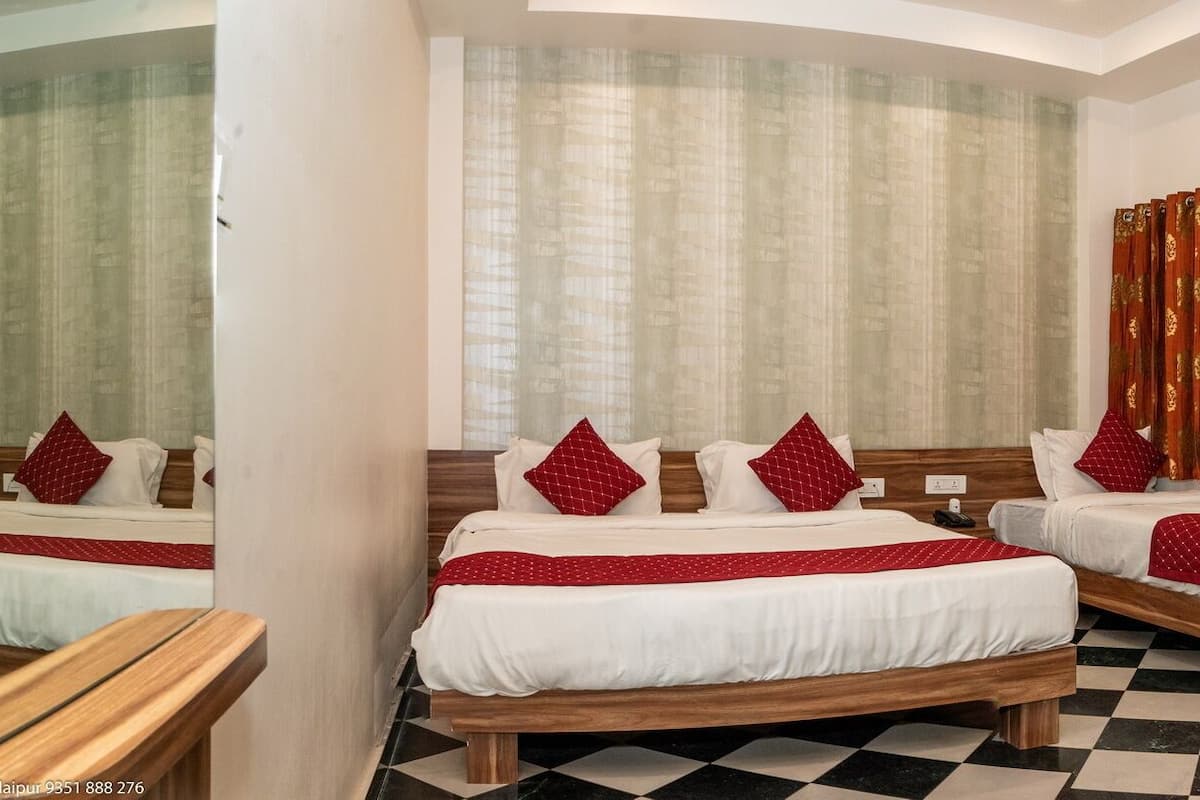 A hotel room with two beds, a wooden wardrobe, and a checkered floor.