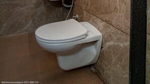 Un baño moderno con inodoro blanco, lavamanos y un perchero para toallas.