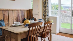 Una mesa de madera con sillas, una tetera amarilla y una taza azul.