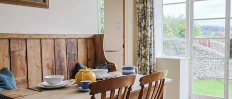 Ein Holztisch mit Stühlen, eine gelbe Teekanne und eine blaue Tasse.