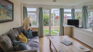 Una sala de estar con un sofá, una mesa de centro, un televisor y un cuadro en la pared.