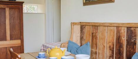 A wooden dining table with blue and white striped cups, a yellow teapot, and a plaid tablecloth.