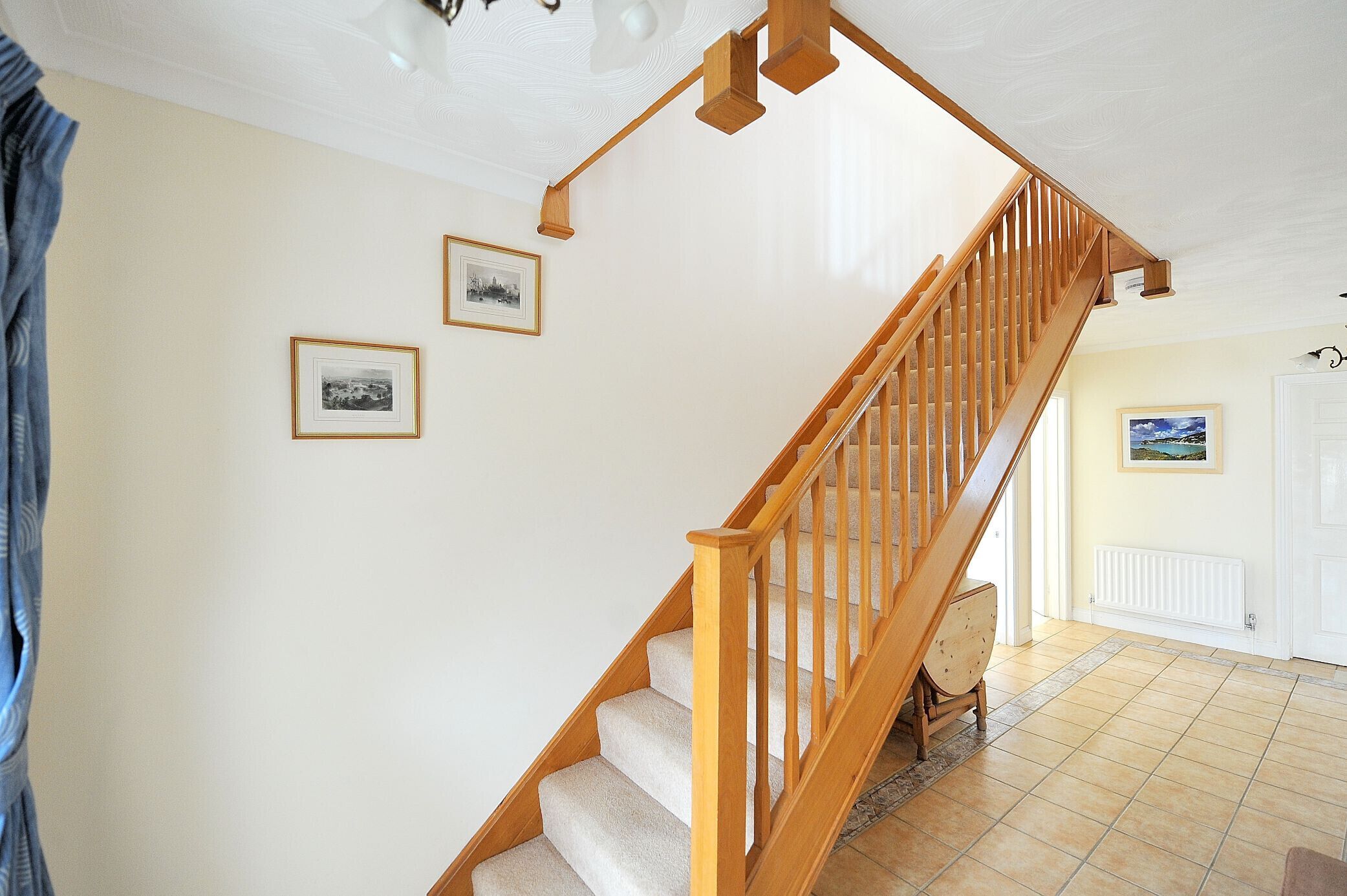 A staircase with wooden railings and carpeted steps, leading to a room with a white door and a framed picture on the wall.